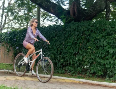 Mulher sorri enquanto anda em uma bicicleta.
